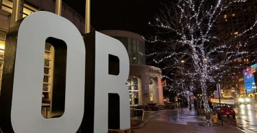 OR sign in front of building with tree lights near street