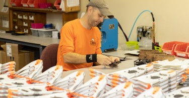 person next to many pairs of snowshoes in factory