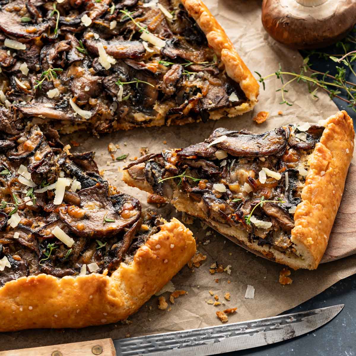 Slices of mushroom galette on a parchment paper with thyme garnishing them on top.