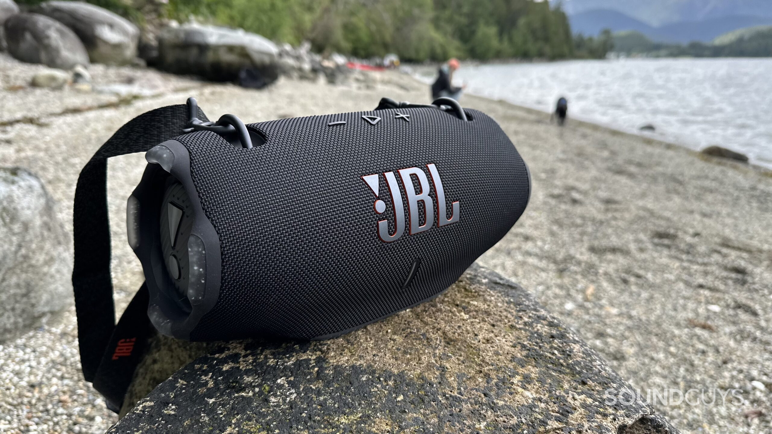 A JBL Xtreme 4 placed on a rock at the beach.