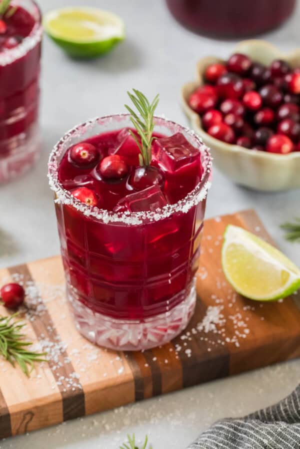 Sparkling cranberry mocktail in a glass on a small cutting board for serving.