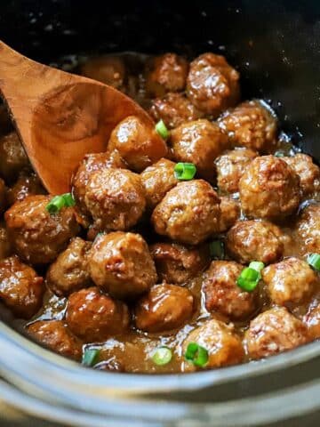 slow cooker with teriyaki meatballs topped with green onions.