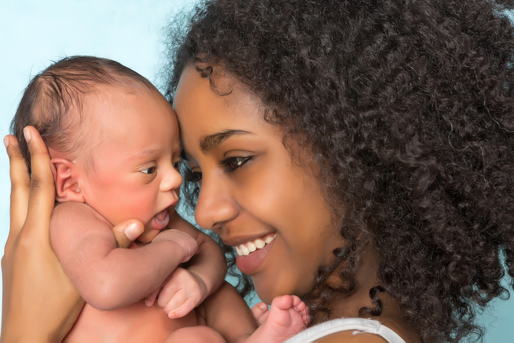 Smiling African mother holding her 11 days old newborn baby