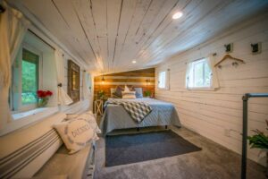 The bedroom, with double bed, bedside cabinets on both sides, four windows and various ceiling and wall lights.