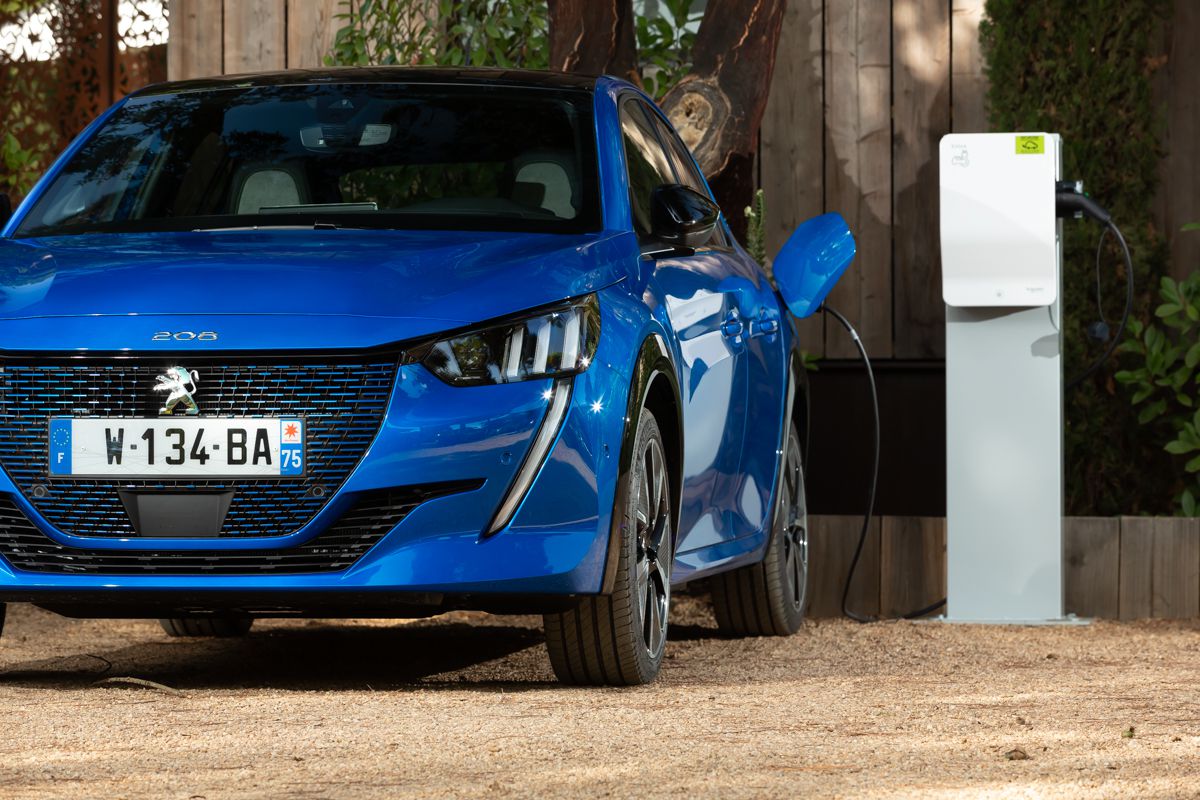 Blue Peugeot e-208 plugged into charger