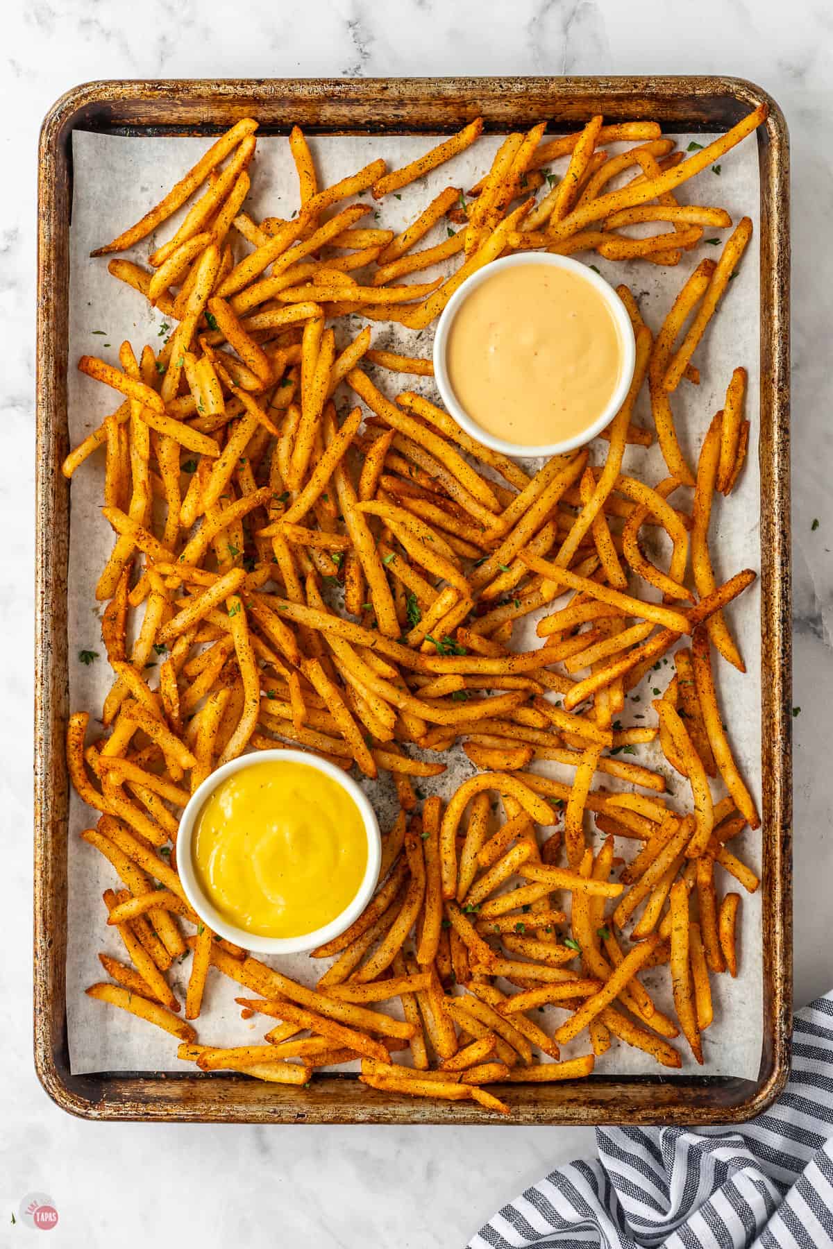 sheet pan of french fries with two bowls of dipping sauce