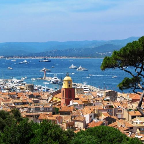 The village of St Tropez and its bell tower with the bay of St Tropez and its luxurious charter yachts at anchor