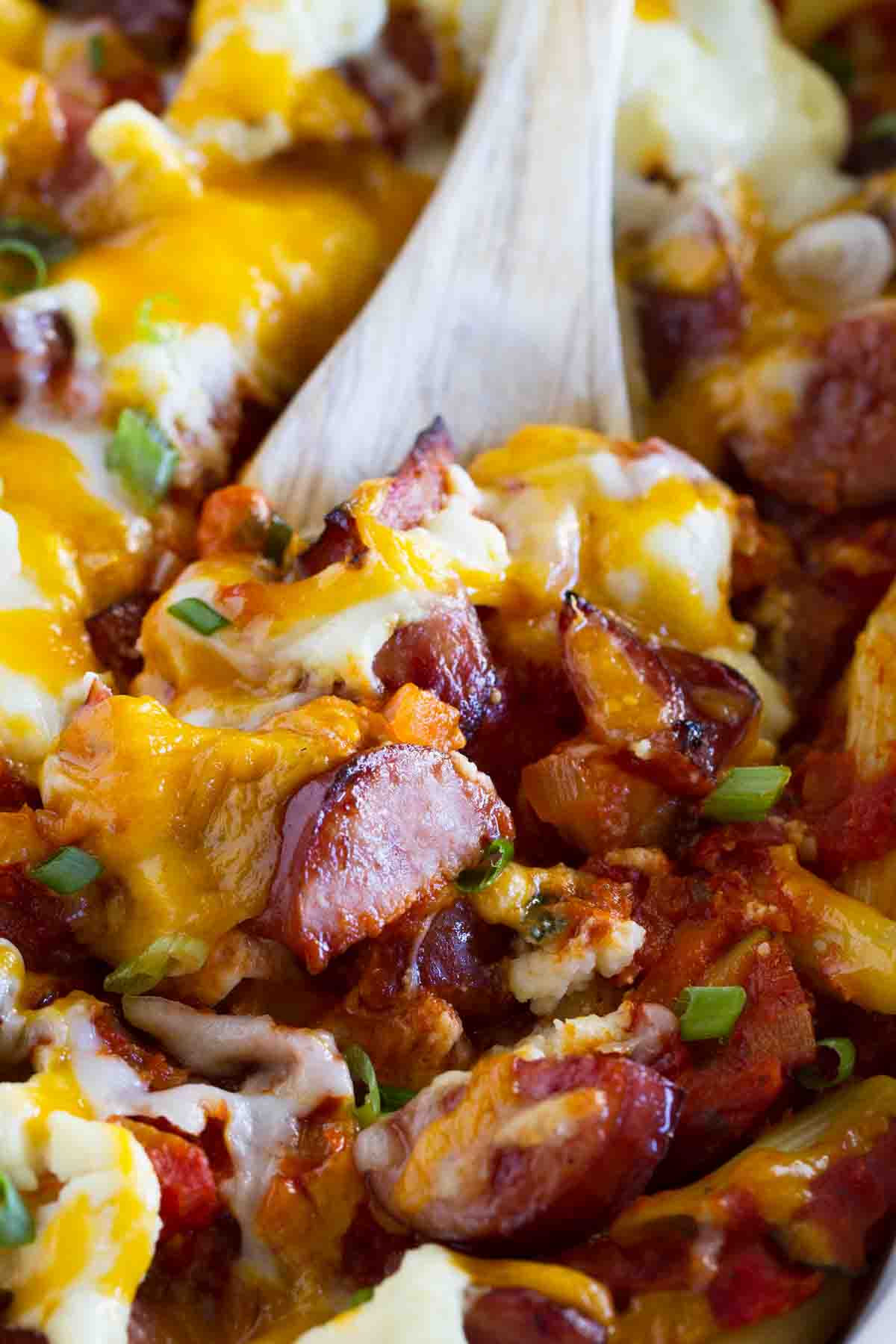 close up of Cheesy Kielbasa Pasta with a wooden spoon