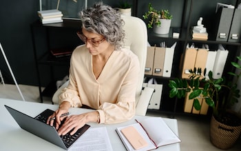 Woman in home office on laptop calculating how to calculate buying out share of house from spouse after divorce