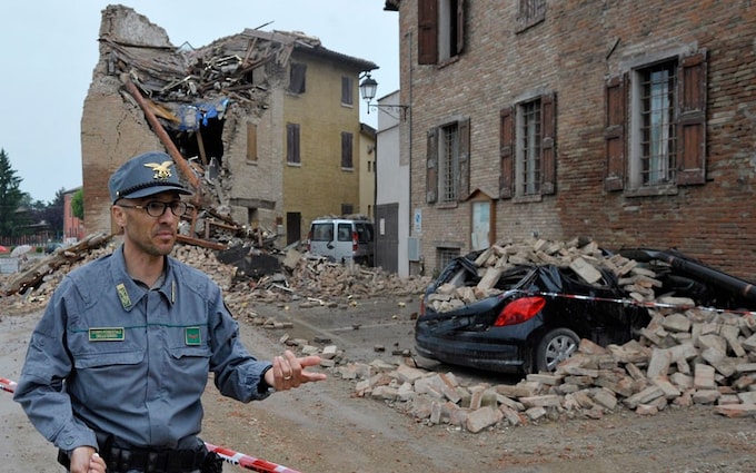 A police officer walks past damaged buildings in San Felice Panaro