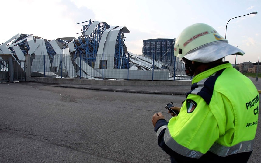 A rescue worker patrols in front of a ceramics factory building which was damaged in the earthquake in Sant' Agostino, near Ferrara