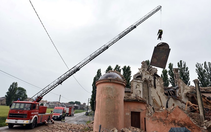 Firemen recover a painting from a destroyed church in the village of San Carlo