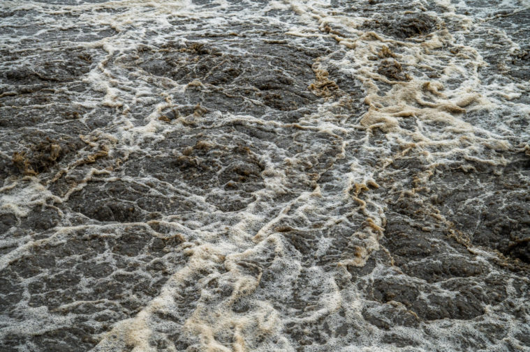 Clean and dirty water mix together in a frothy mixture of water from the Brazos River.