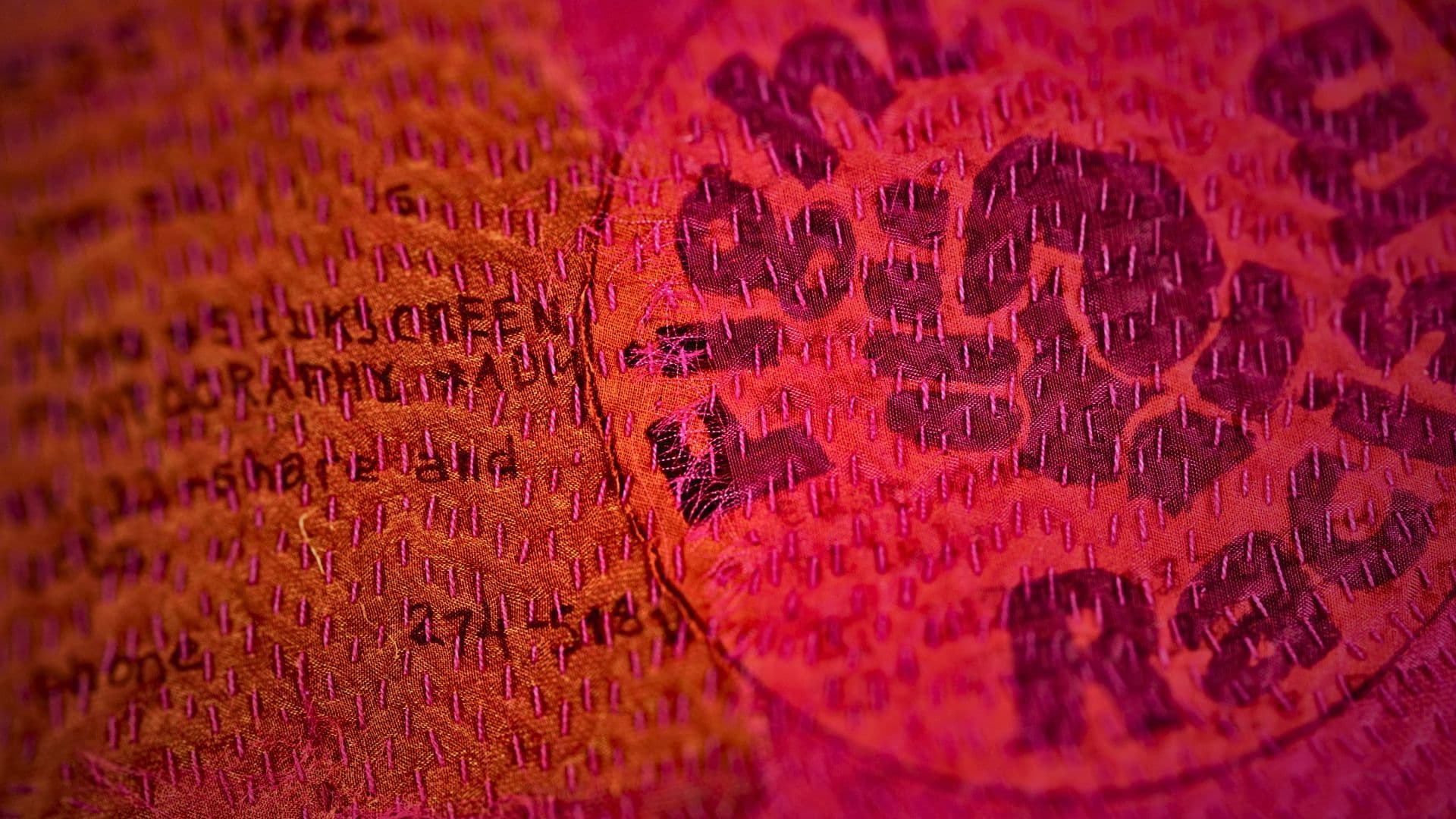 A close up of a stitched artwork embellished with the words 'fight racism' and a raised fist symbol.