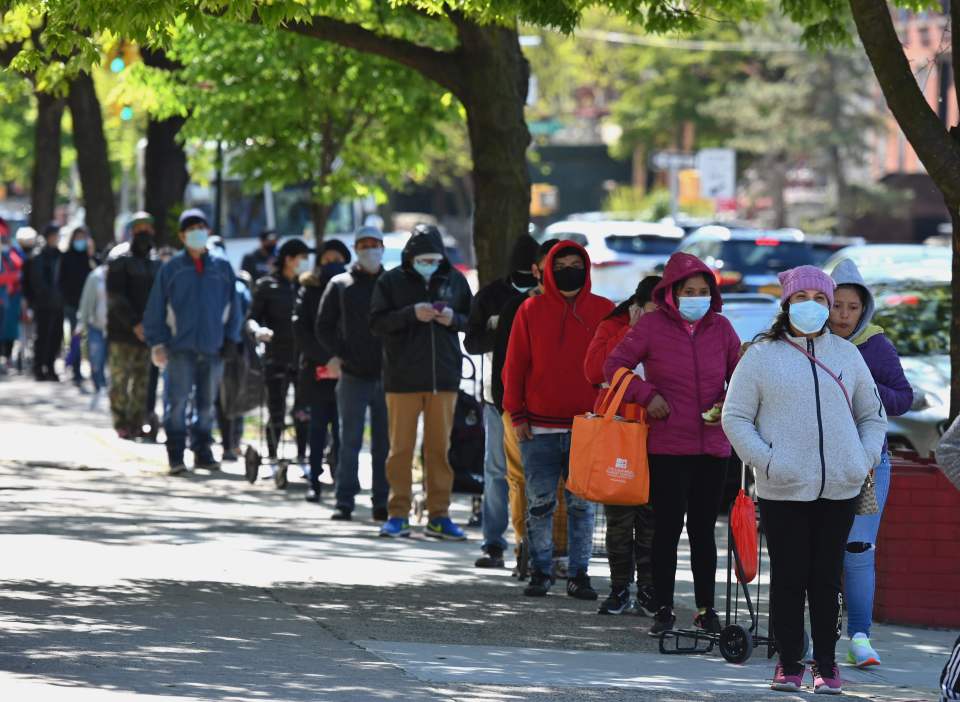 People wait in line as members of the US Army National Guard hand out food and other essentials at a food pantry in Brooklyn on May 13, 2020