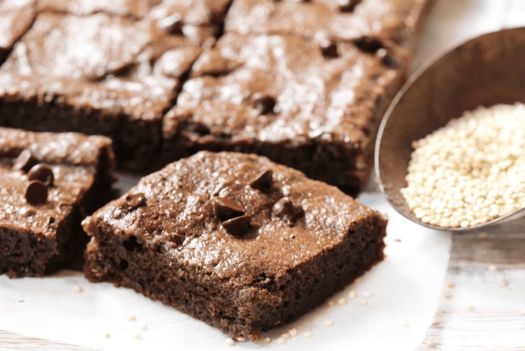 chocolate chips weed brownies divided into six separate slices on top of a cooking table. A bowl of rice lays across from them. 