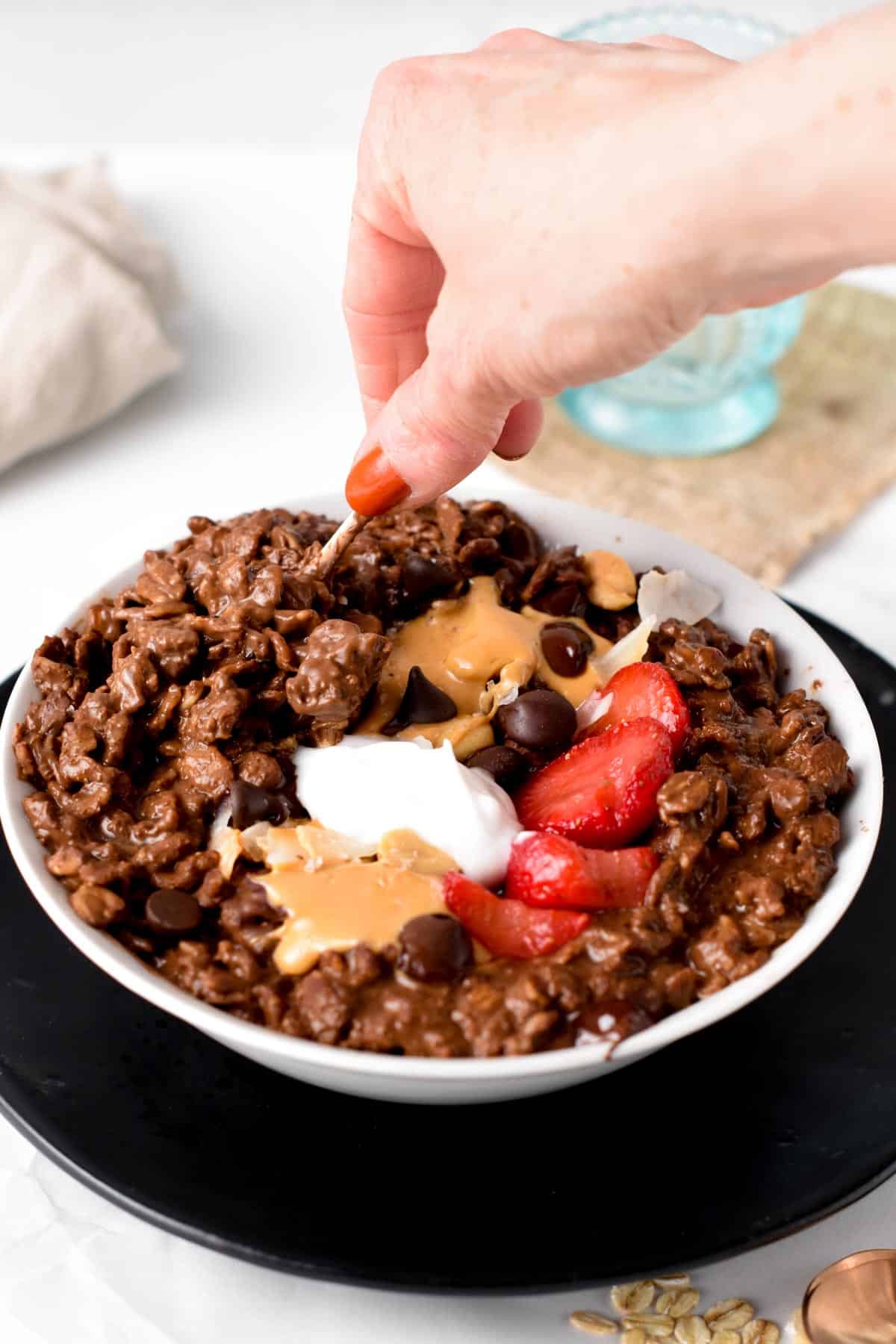 Chocolate Oatmeal in a bowl with my hand holding a golden fork.