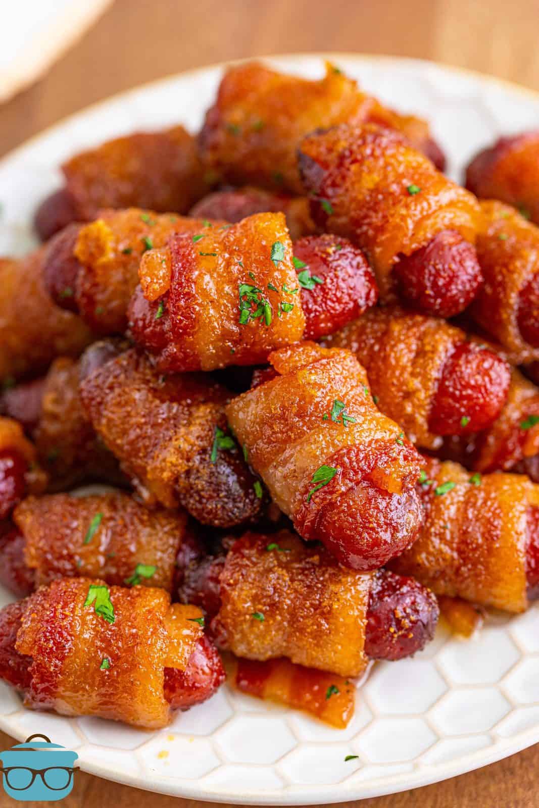 Brown Sugar Bacon Wrapped Little Smokies topped with parsley on white plate.