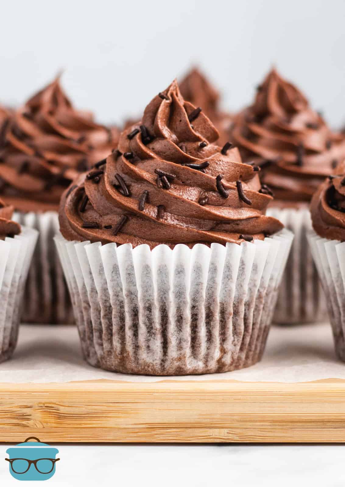 Easy Chocolate Cupcakes topped with sprinkles on wooden platter.