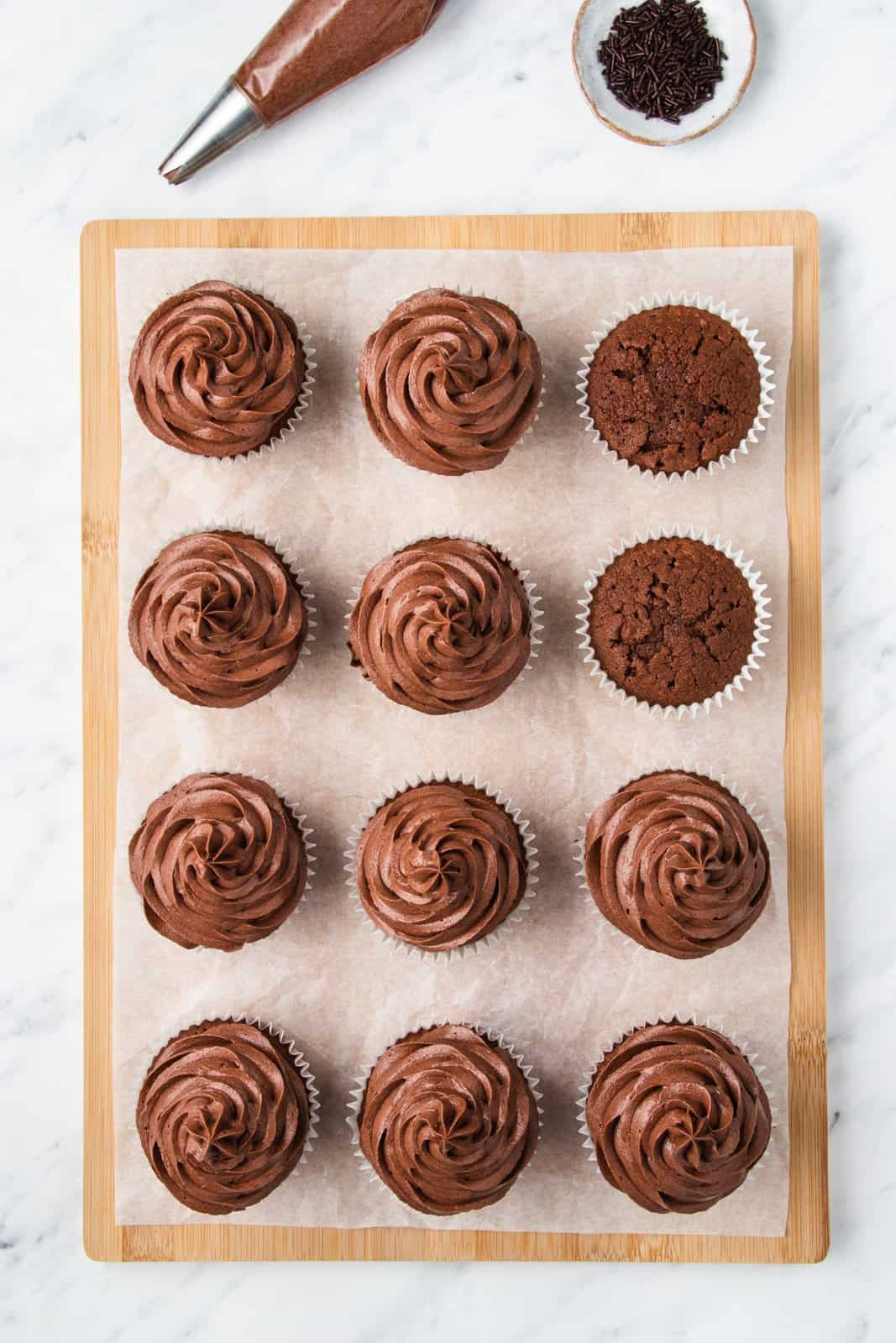 Cupcakes cooled and being frosted and decorated.