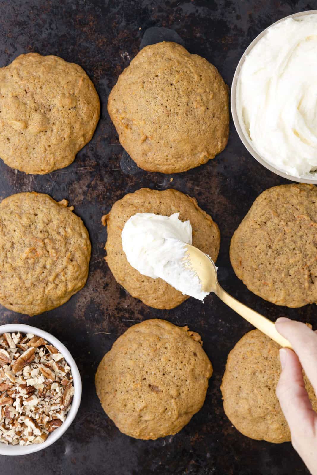 Carrot Cake cookies with frosting being spread out on one. 