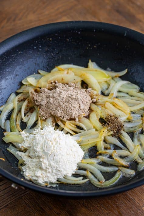 flour, brown gravy mix and black pepper added to sliced onions in a skillet.