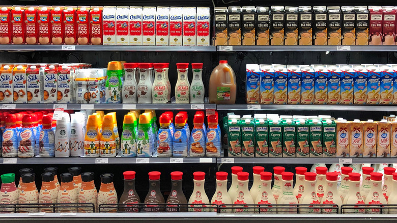 grocery store refrigerator shelves stocked with a variety of eggnog brands