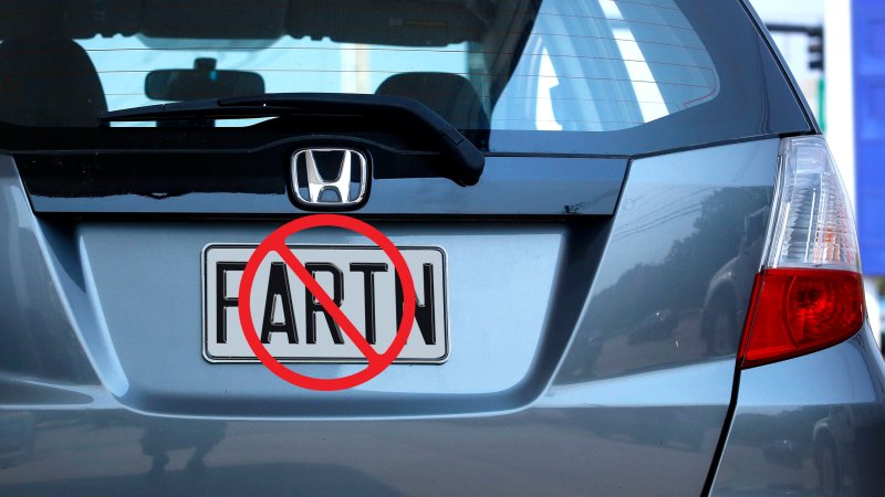 A close-up on a Honda Fit's rear license plate, where the plate has been modified to read "FARTN," and there is a circular stop sign on top of it, indicating that it is not allowed.