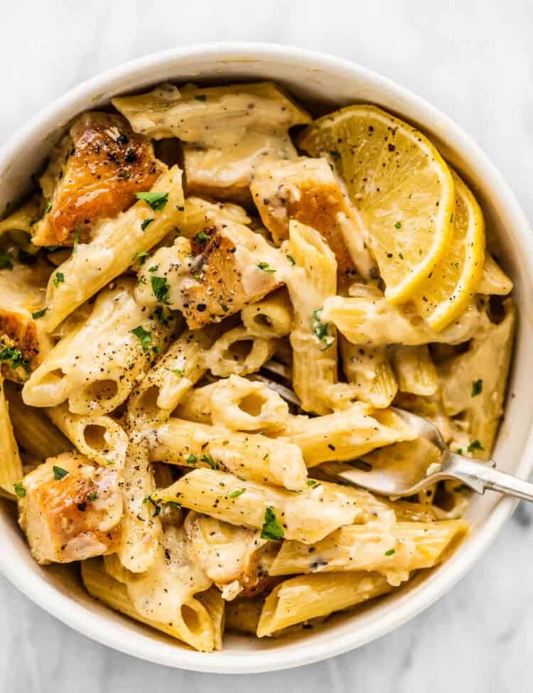 Lemon chicken pasta in a white bowl with a fork,