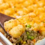 A serving spoon scooping tater tot casserole.