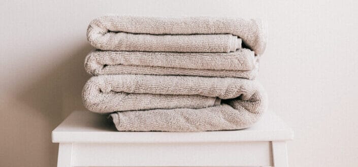 Stack of light beige towels on white stool