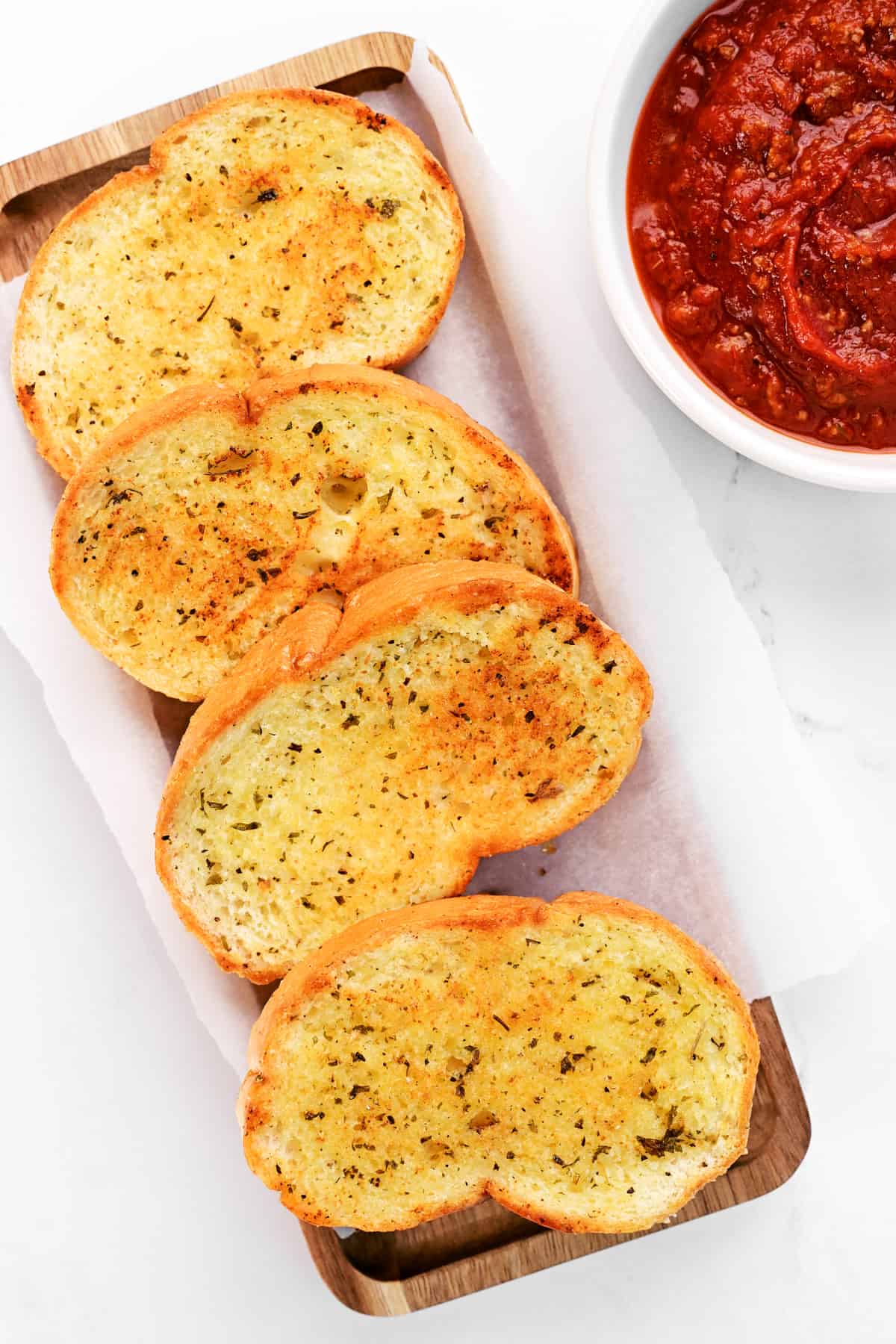 Four Texas Toast garlic bread pieces lined up on a tray.