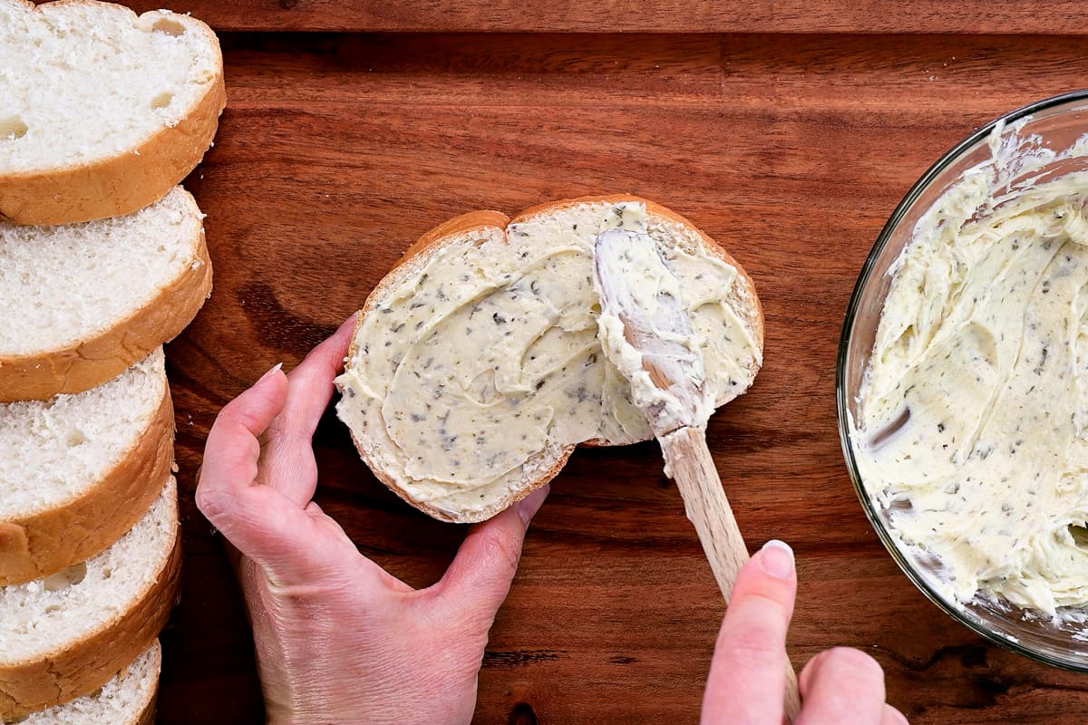 hands shown adding garlic butter to a slice of Texas toast.