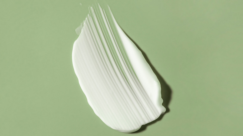 Cream face mask sitting on a green background