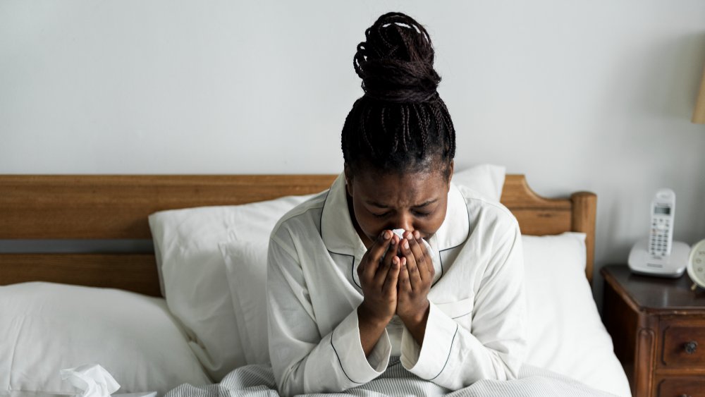 A woman in bed blowing her nose