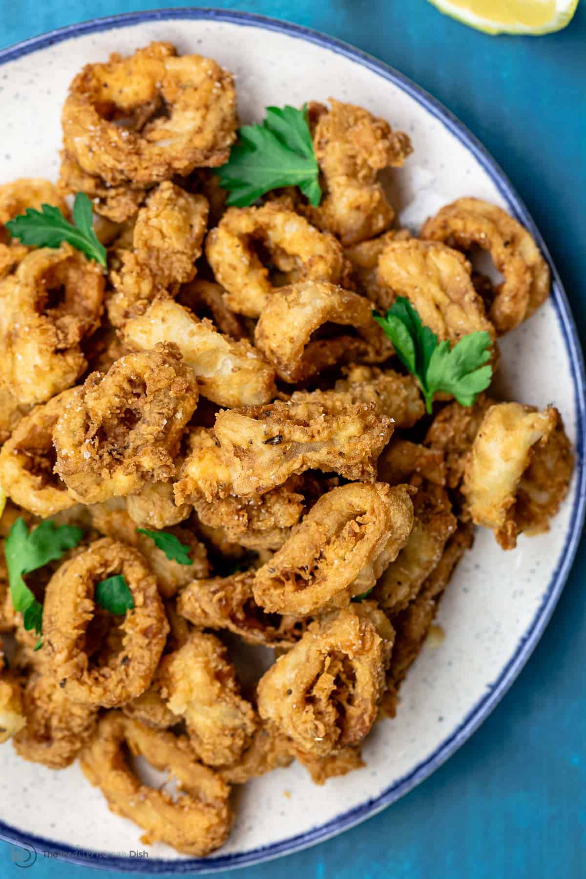 Fried calamari served on a plate atop a blue table