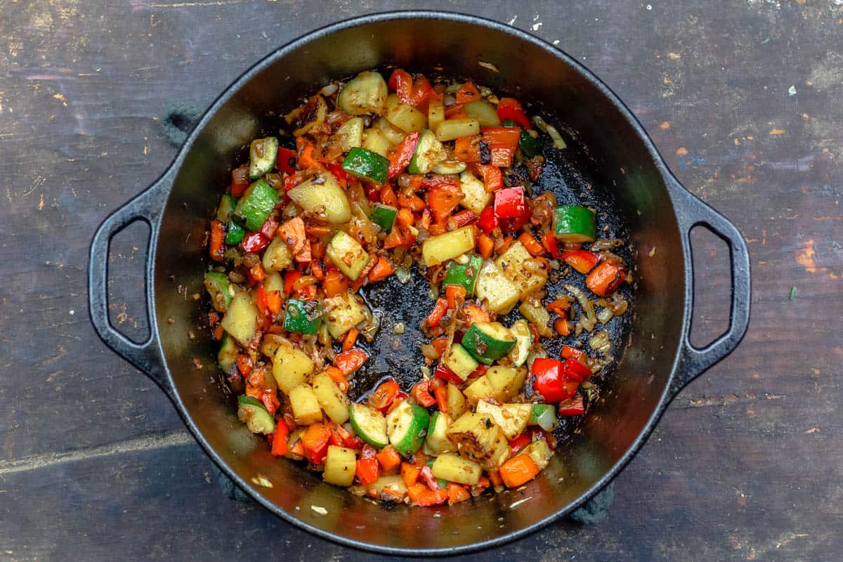 chopped vegetables for chicken stew sauteeing in a large pot.