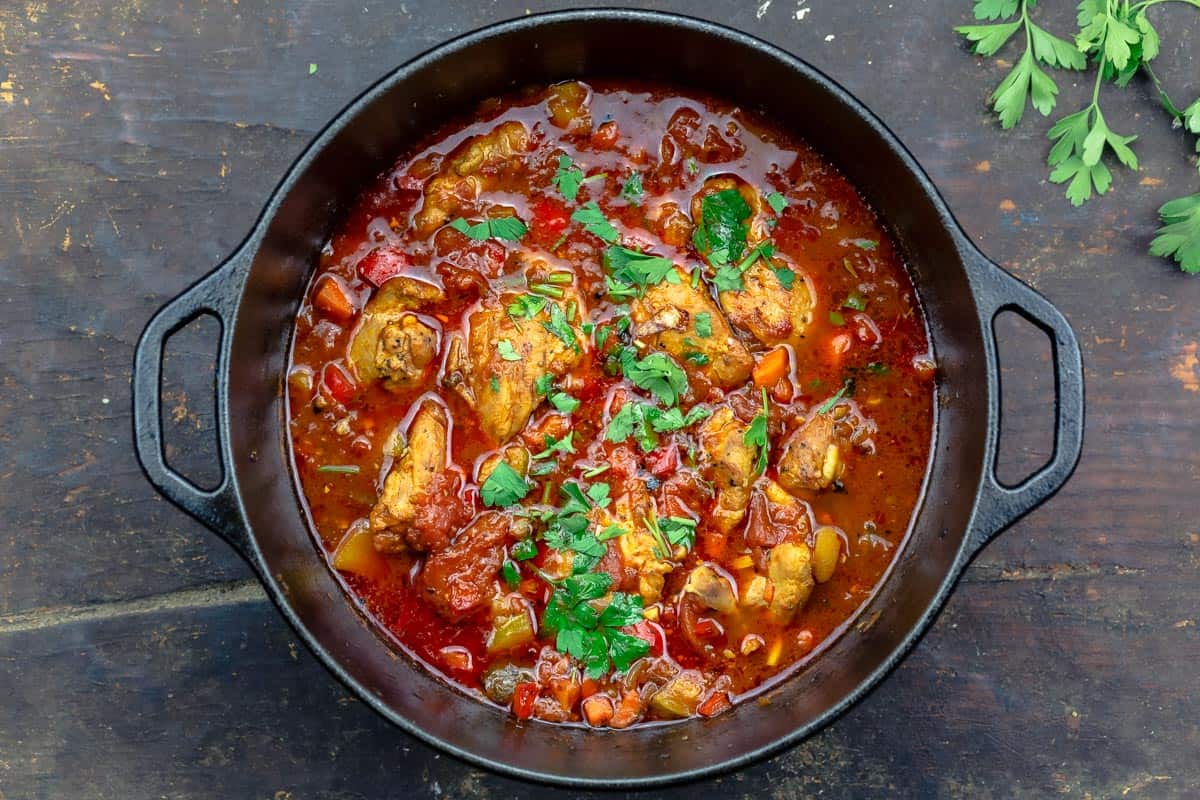 chicken stew garnished with parsley in a large pot.