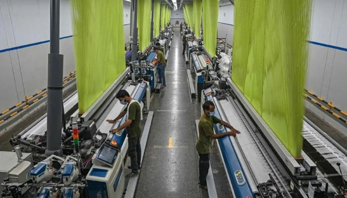 This Representational image shows Workers operating a machine preparing fabric at the Kohinoor Textile Mills in Lahore. — AFP/File