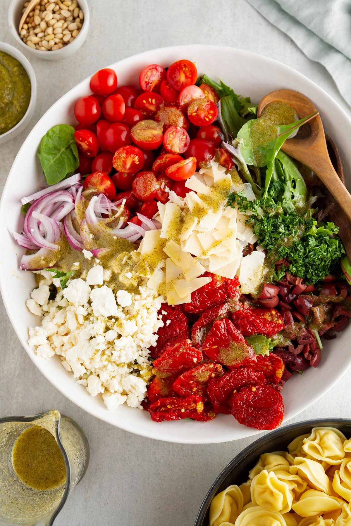 Ingredients for tortellini salad in a large serving bowl.