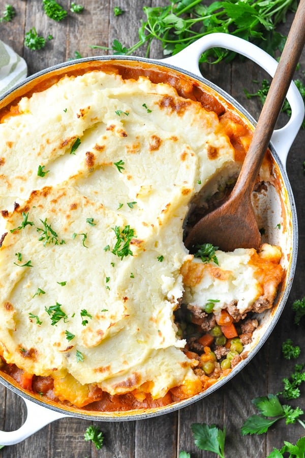 An overhead image of a round casserole dish filled with Cottage Pie casserole - a ground beef casserole topped with a layer of mashed potatoes.