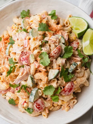 Mexican macaroni salad with ham in a bowl with some lime wedges.