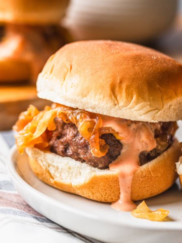 Air fryer slider on a plate with burger sauce dripping over the patty.