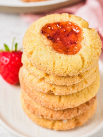 Christmas thumbprint cookie stacked on a plate.