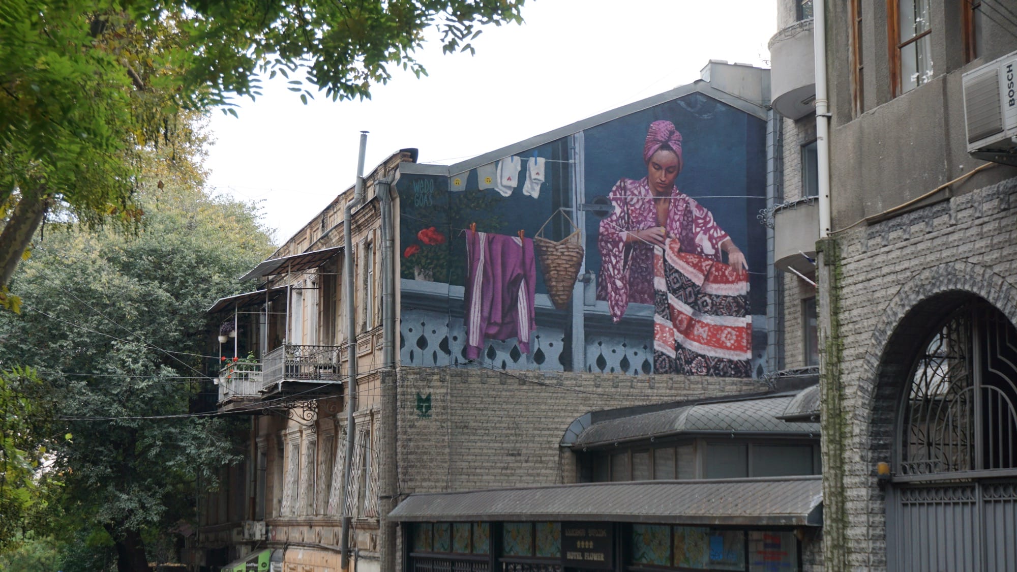 a large mural on the side of a building of a woman hanging out her laundry