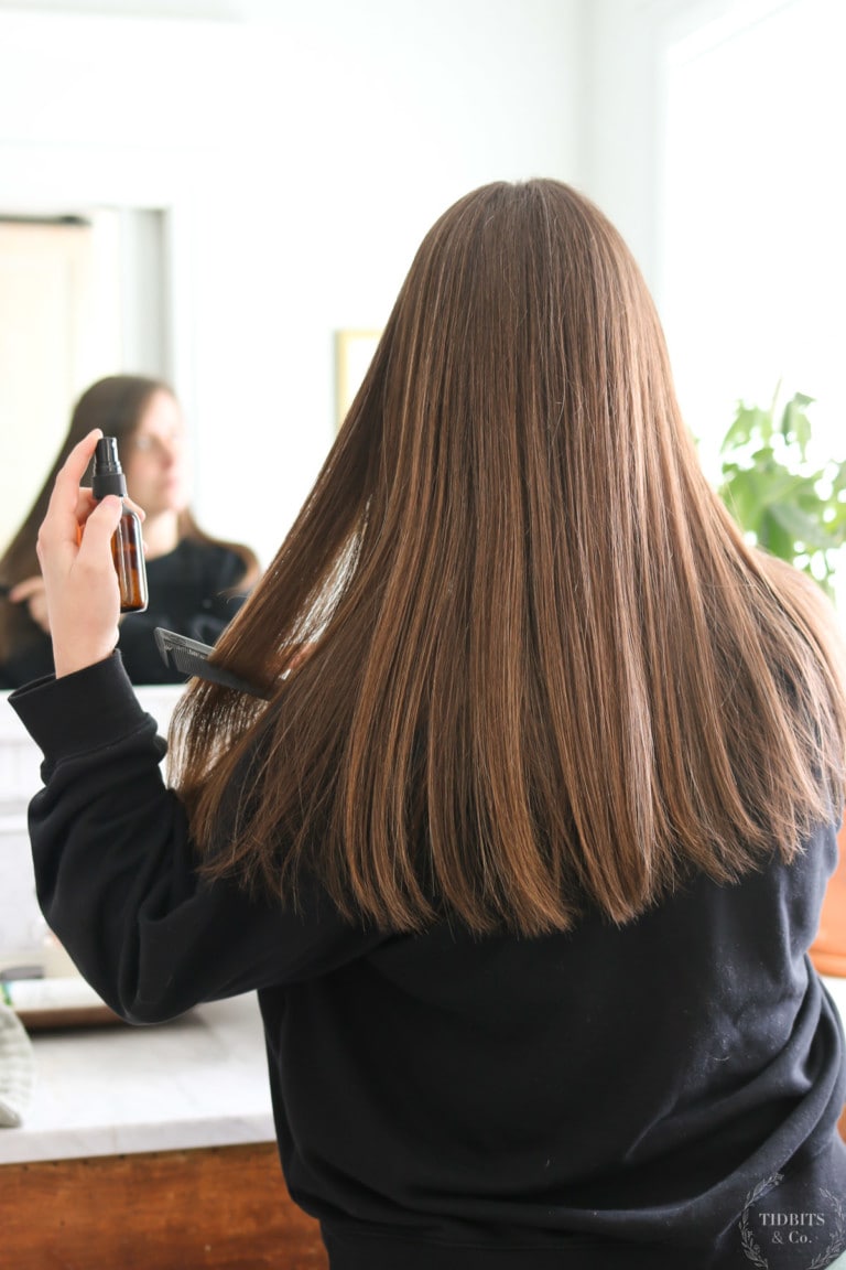 A woman sprays natural heat protectant on her hair