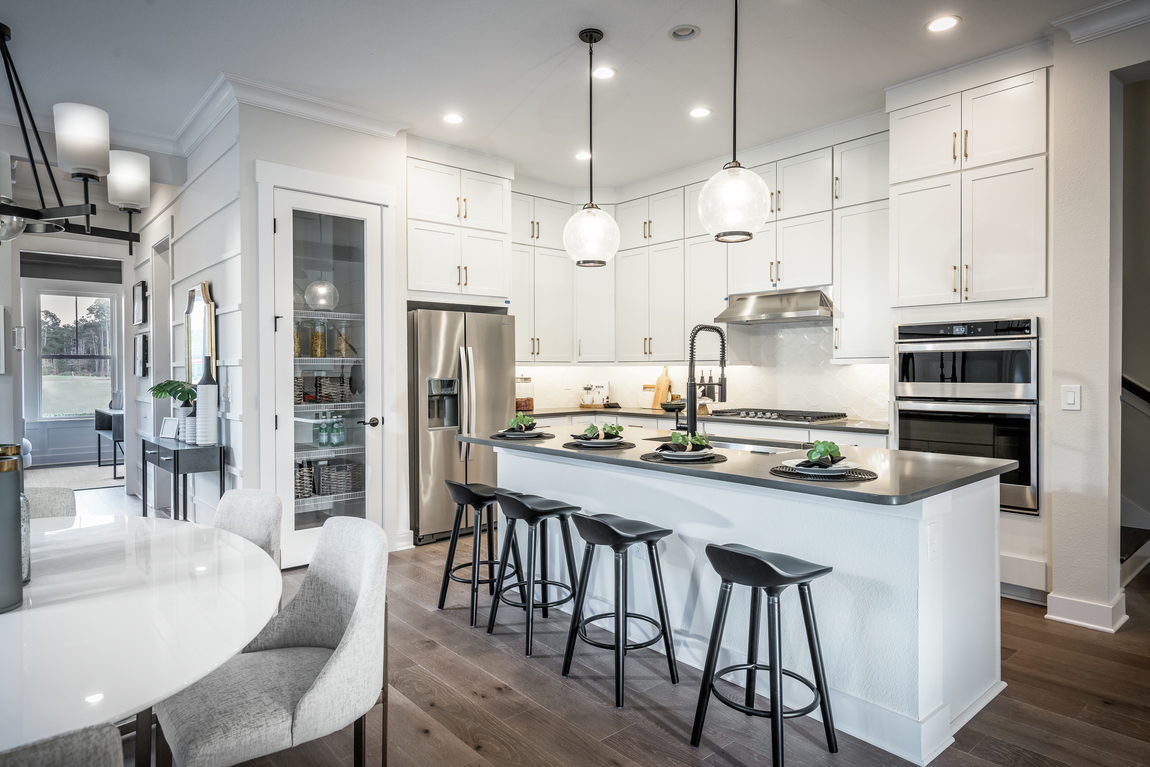 Luxury kitchen with white cabinets and four barstools along a tall kitchen island.