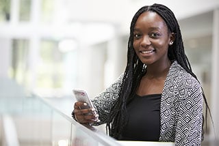 Young woman using laptop at desk in bright office setting.