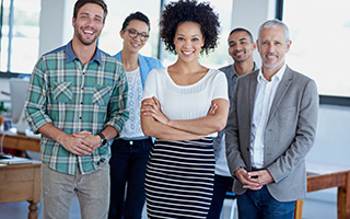 Group of five diverse business professionals smiling in an office setting