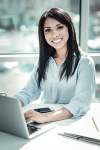 Woman using laptop at desk in bright office setting